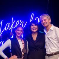 President Mantells poses for a photo with two grads in front of the Laker for a Liftetime neon sign